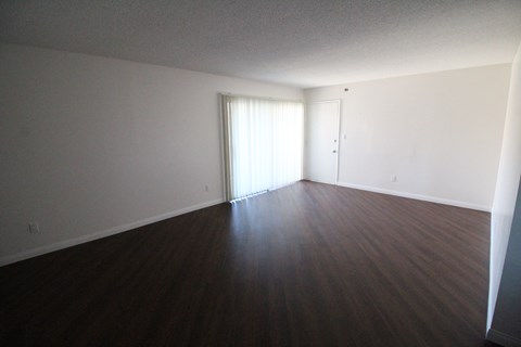 an empty living room with wood floors and white walls