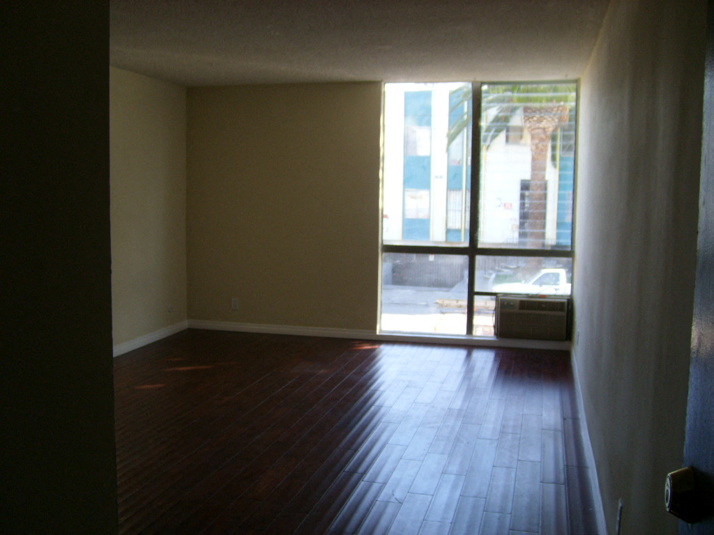 an empty living room with wood floors and a window