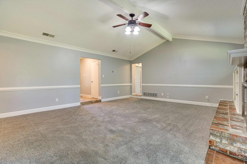 an empty living room with a ceiling fan