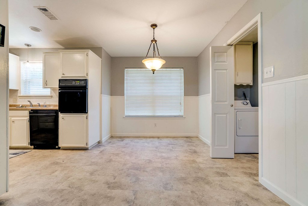 an empty kitchen and laundry room with a light hanging from the ceiling