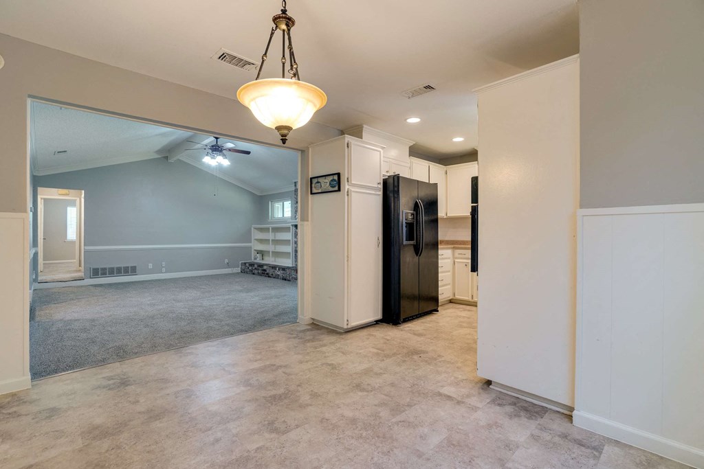 an empty kitchen and living room with a refrigerator in the middle