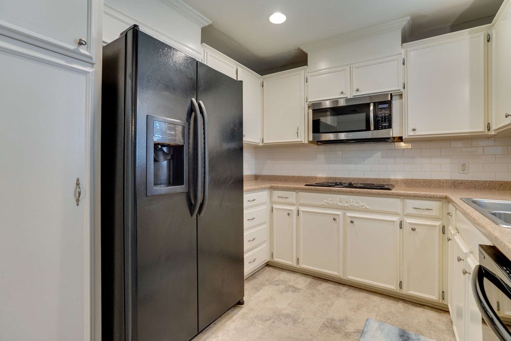 a kitchen with white cabinets and a stainless steel refrigerator