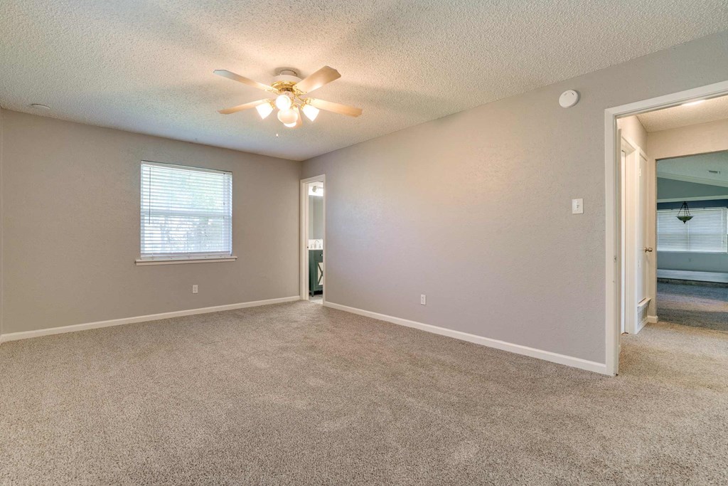 an empty living room with a ceiling fan