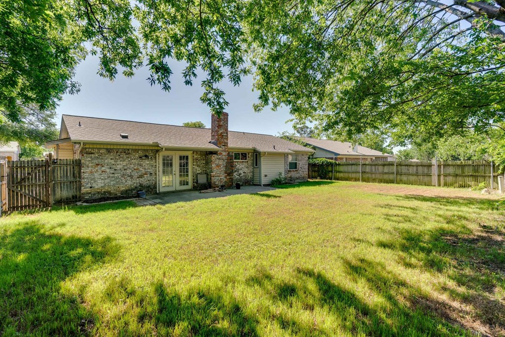 a small brick house with a yard and a fence