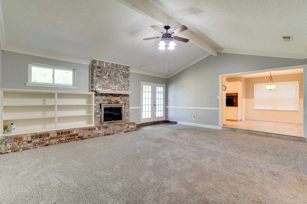 an empty living room with a fireplace and a ceiling fan