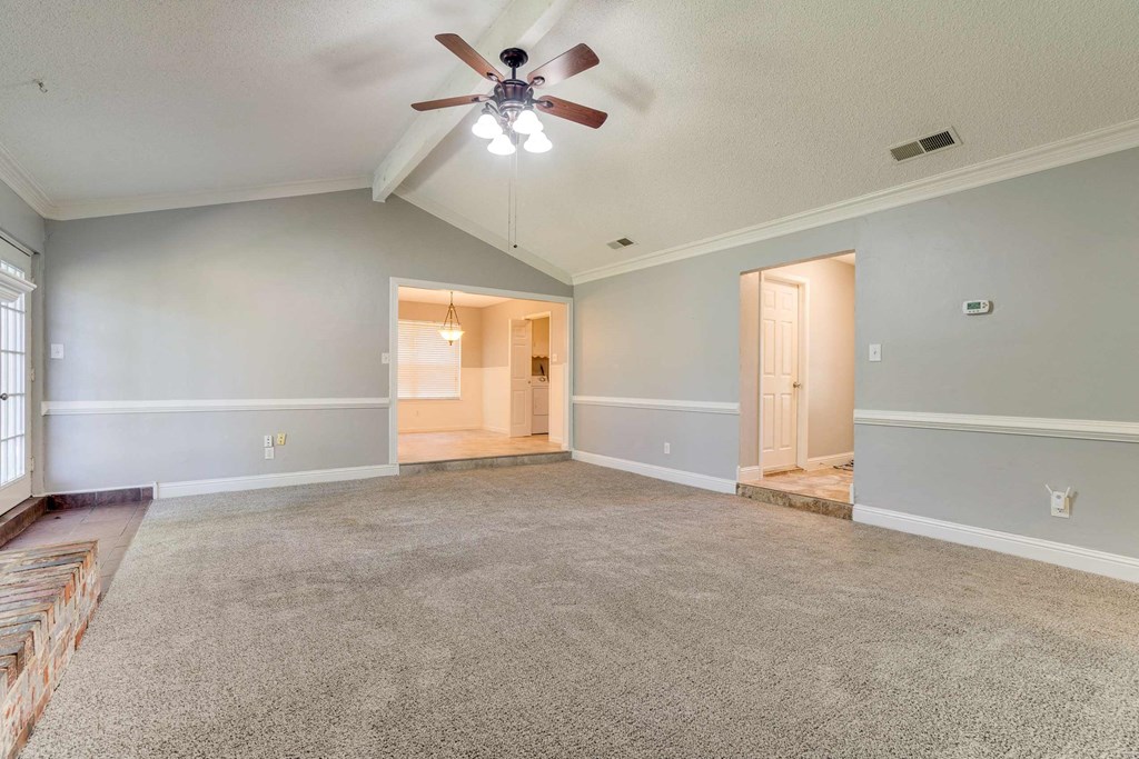an empty living room with a ceiling fan