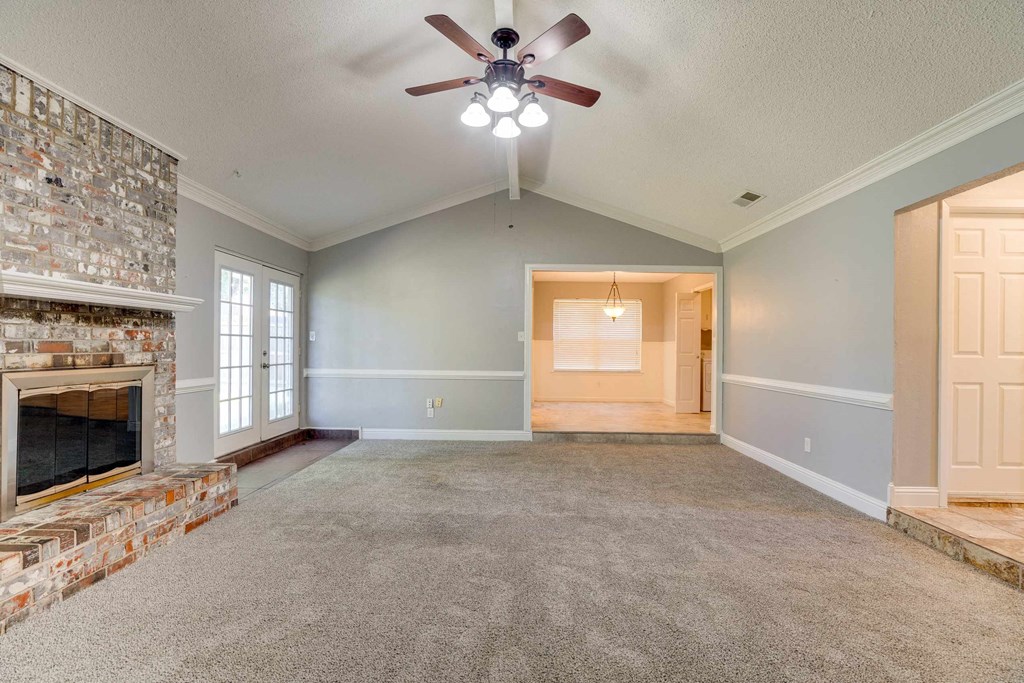 an empty living room with a fireplace and a ceiling fan