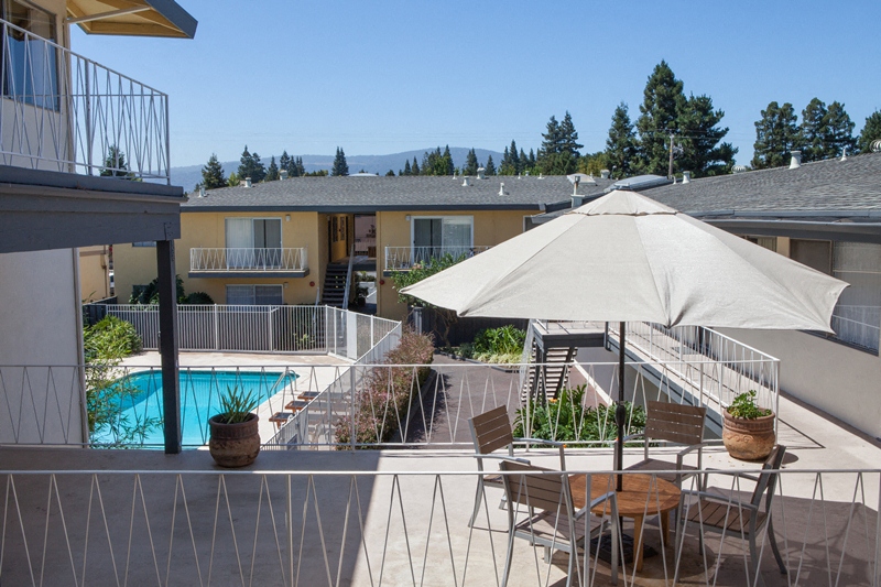 a view of a pool and a patio with chairs and an umbrella