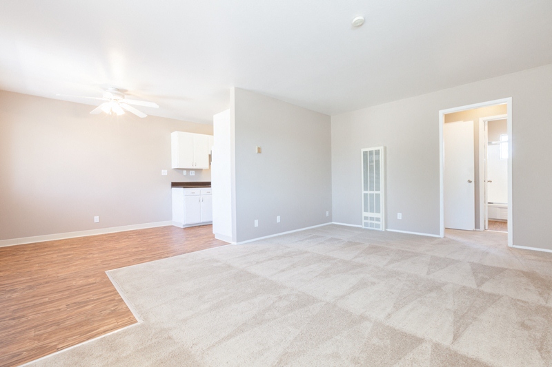 the spacious living room and dining room of an empty apartment