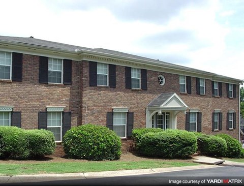 a brick building with a porch and some bushes