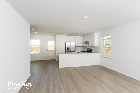 A spacious kitchen with white cabinets and a wooden floor.