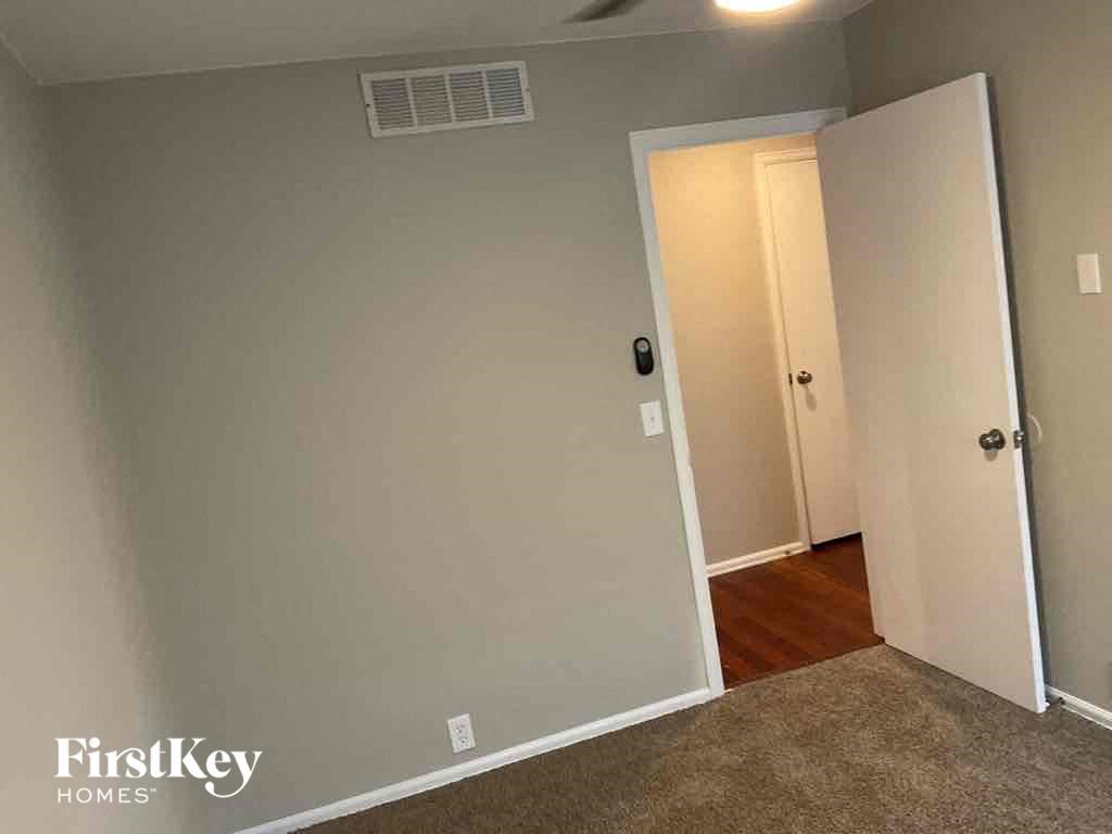 an empty room with a door open to a hallway and a closet