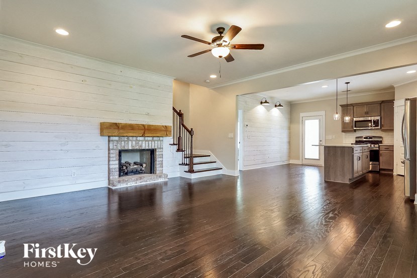an empty living room with a fireplace and a ceiling fan