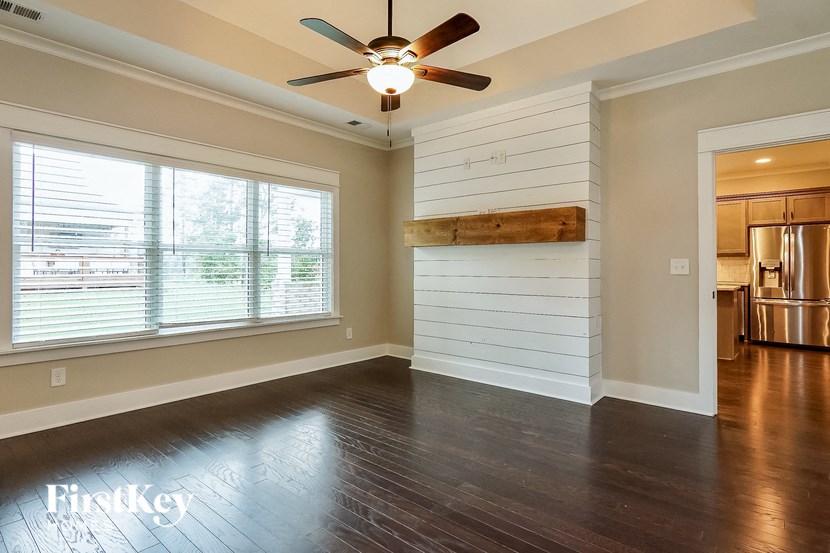 an empty living room with a ceiling fan and a large window