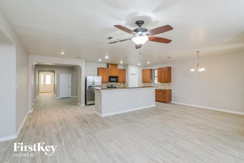 A spacious kitchen and living room with a ceiling fan and lighting fixtures.