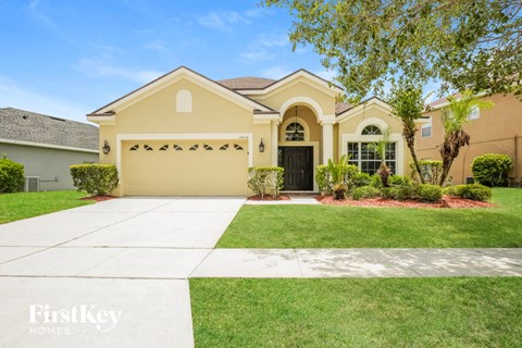 a yellow house with a lawn and a driveway