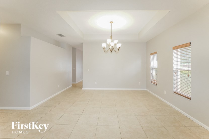 an empty dining room with a chandelier and windows