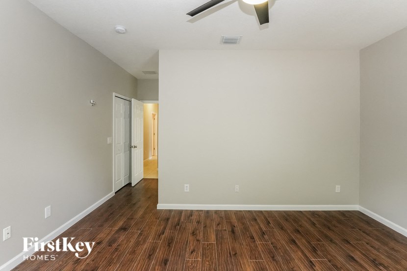 an empty living room with wood flooring and a ceiling fan