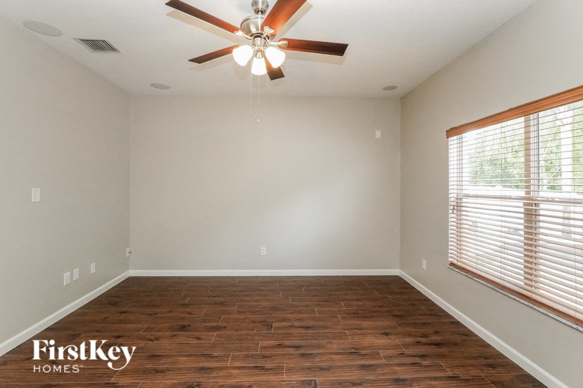 the living room with wood flooring and a ceiling fan