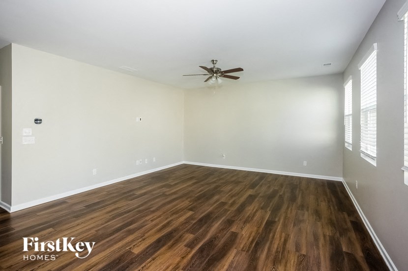 an empty living room with wood flooring and a ceiling fan
