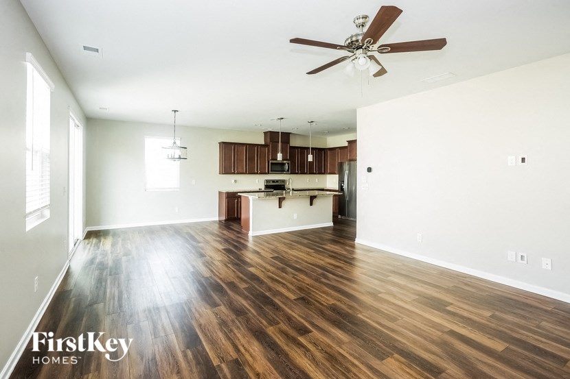 an empty living room and kitchen with a ceiling fan