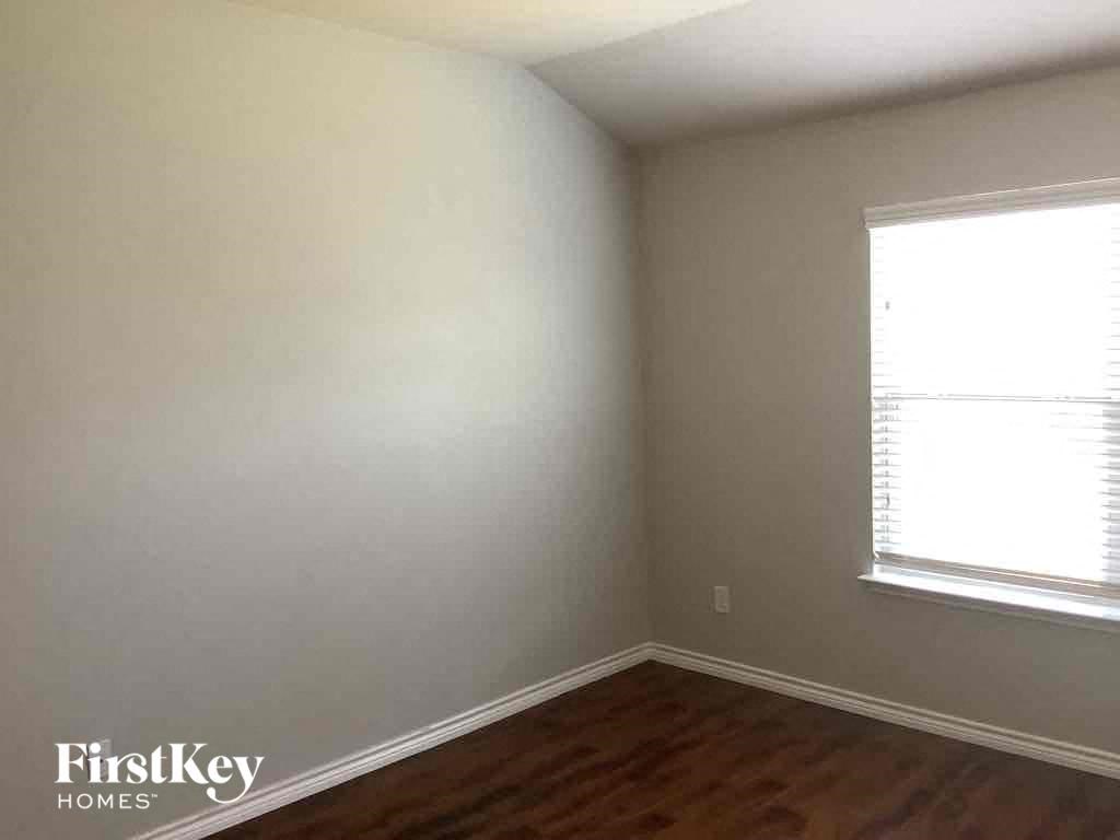 a small room with white walls and a window and wooden floors