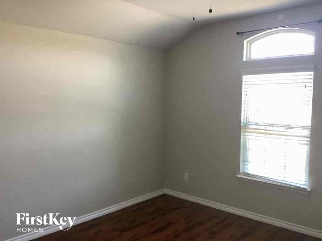 an empty room with a window and wooden floors
