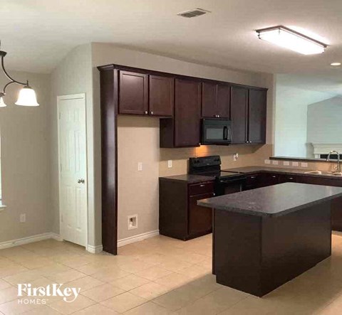 an empty kitchen with dark cabinets and a counter top