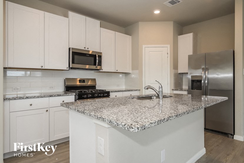 a kitchen with white cabinets and a marble counter top