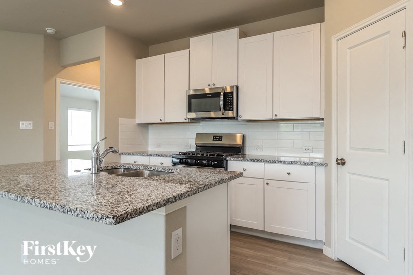 a kitchen with white cabinets and a granite counter top