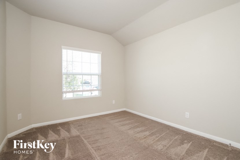 a bedroom with a window and a carpeted floor