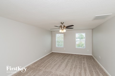 a spacious living room with carpet and a ceiling fan