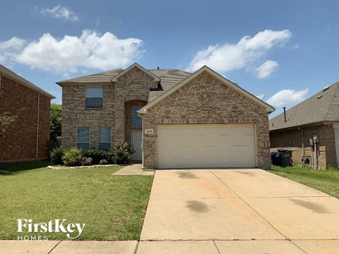 A brick house with a garage door and a sign that says FirstKey Homes.