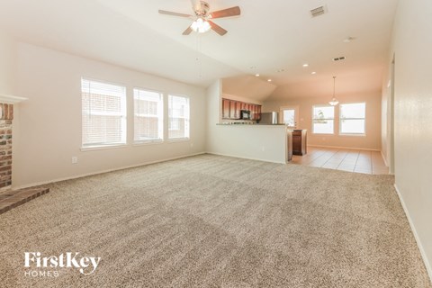 A spacious room with a carpeted floor and a ceiling fan.