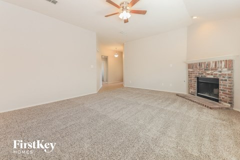 A spacious living room with a fireplace and a ceiling fan.
