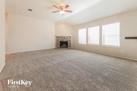 A spacious room with a fireplace and a ceiling fan.