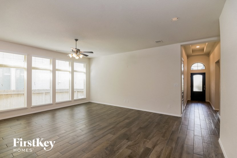 an empty living room with large windows and a ceiling fan