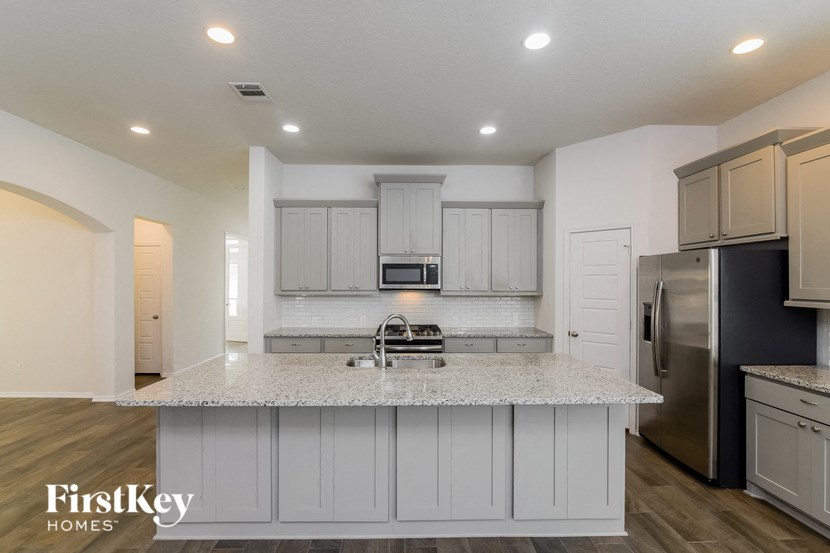 a kitchen with white cabinets and a marble counter top