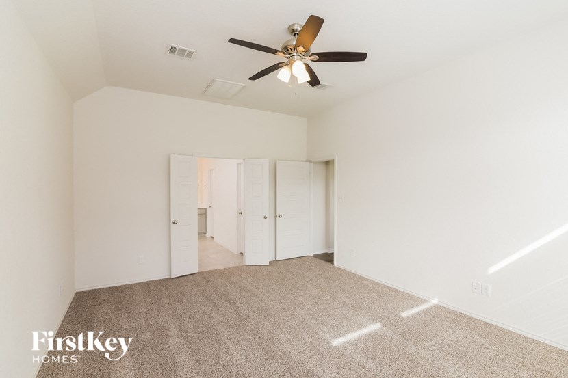 a spacious living room with carpet and a ceiling fan