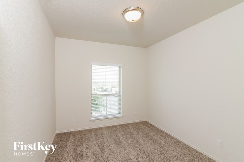 a bedroom with white walls and carpet and a window