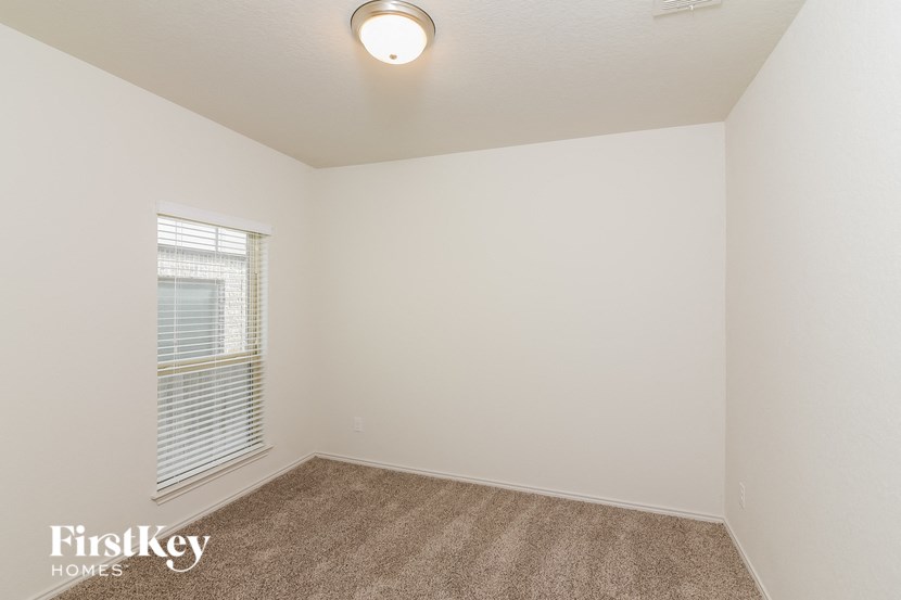 a bedroom with white walls and carpet and a window