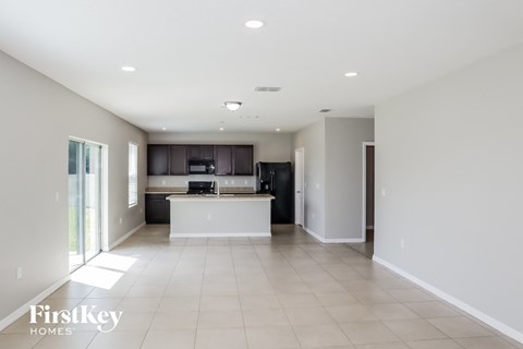 A spacious kitchen with a white island and a black refrigerator.