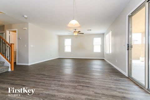 an empty living room with wood floors and a ceiling fan