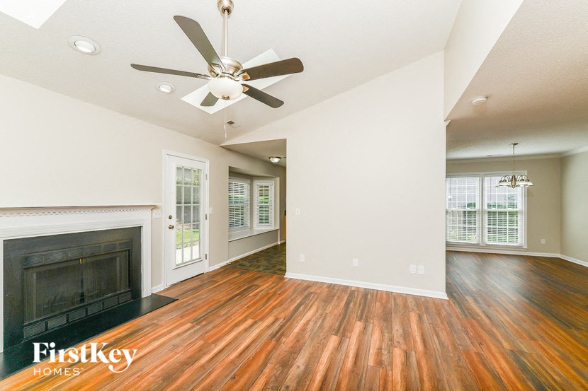 an empty living room with a fireplace and a ceiling fan