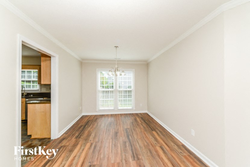 an empty living room with wood flooring and a kitchen