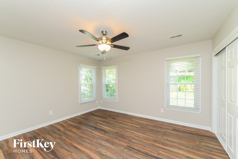 an empty living room with a ceiling fan and windows