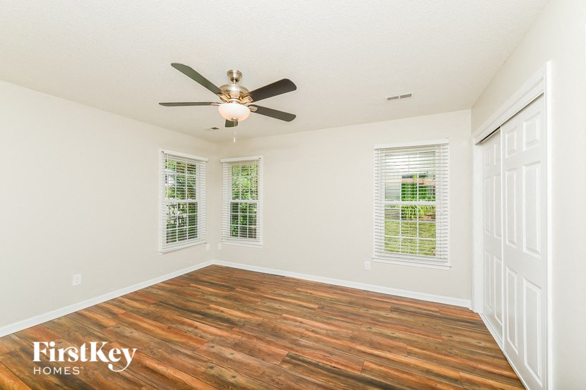an empty living room with a ceiling fan and windows