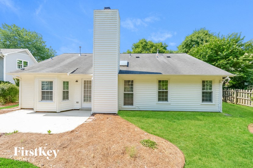 the front of a white house with a yard and a chimney