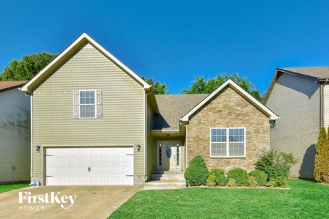 a tan house with a white garage door and a green lawn