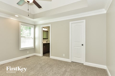 a bedroom with a ceiling fan and a door to the bathroom